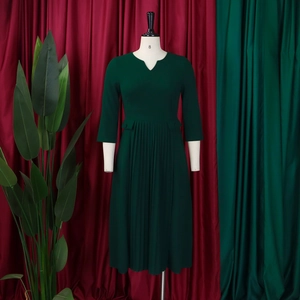Close-up of pleated dark green dress featuring half sleeves and decorative pocket flaps