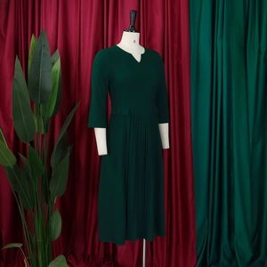 Detail of V-neck dark green pleated midi dress with three-quarter sleeves on mannequin