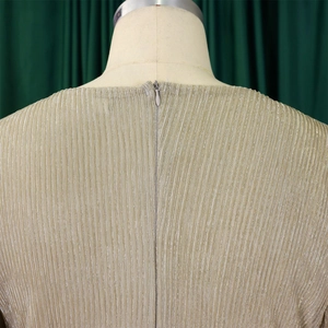 Detail view of the champagne gold pleated fabric with invisible zipper on the evening dress