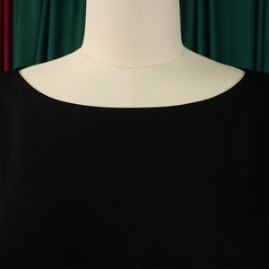 Detail of the wide round neckline on a black wide-leg jumpsuit with fine stitching