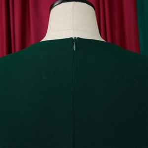 Detail of the high-quality invisible zipper on the back collar of a dark green pleated dress