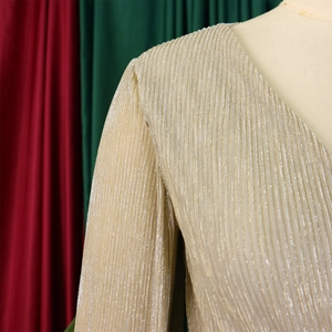 Detailed view of champagne gold pleated fabric with metallic sheen and V-neckline texture