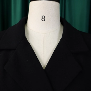 Detailed close-up of a high-waisted pleated blazer dress with classic notched lapels in black