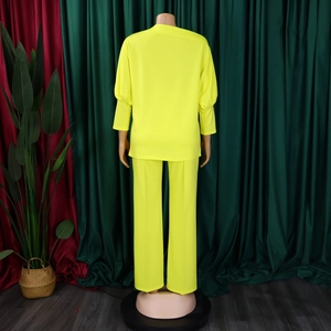 Detail von neongelbem Langarmshirt und Plisseehose aus hochwertigem strukturiertem Stoff
