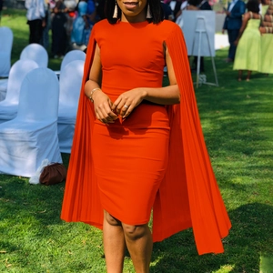 Detailed view of bright orange pleated cape sleeves on an elegant slim fit party dress