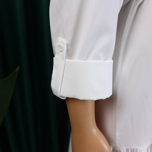 Detail of white shirt dress cuff with buttoned tab and polished cotton fabric texture