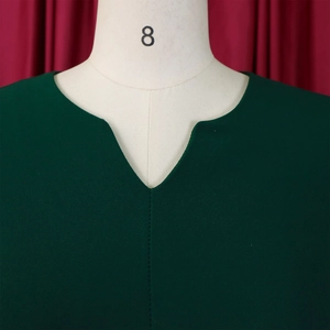Detail of notch V-neckline and center seam stitching on dark green pleated midi dress