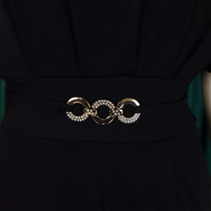 Detail of waist area featuring gold metal rings with rhinestones on black jumpsuit fabric