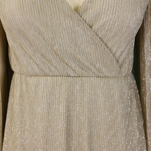Detail of champagne gold pleated dress fabric with metallic shine and deep V-neckline