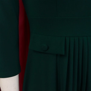Detail of dark green dress showing pleated hem, waist flap, and fabric button accents