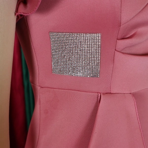 Close-up of pink ruffle dress featuring a square rhinestone patch and premium fabric