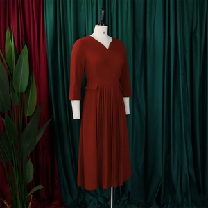 Detail of brick red V-neck dress with pleated hem and three-quarter length sleeves