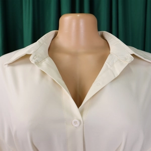 Detailed view of cream-white shirt collar with neat stitching and white button detail