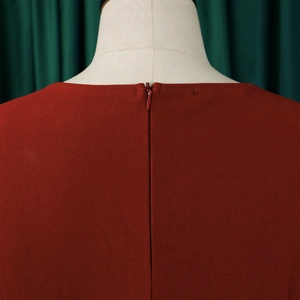 Close-up of invisible zipper detail on the back of a deep red pleated midi dress