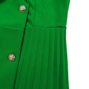 Detail of high-waisted green blazer dress featuring gold crest buttons and pleated texture