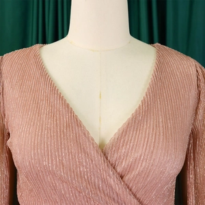 Close-up of elegant rose gold pleated metallic fabric with deep V-neck cross design