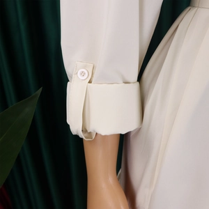 Detail of minimalist buttoned cuff on a cream long-sleeve casual shirt dress