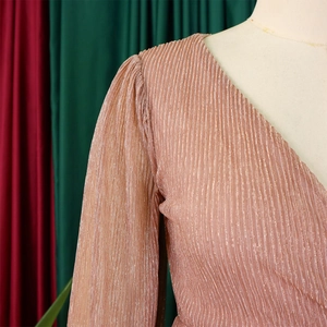 Close-up of rose gold pleated V-neck evening dress with metallic texture and long sleeves