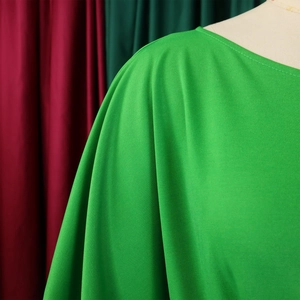 Detailed view of bright green jumpsuit with pleated shoulder design and textured fabric