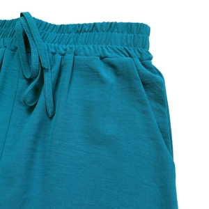 Detail of teal casual shorts showing elastic waistband with drawstring and side pockets