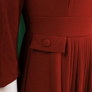 Close-up of wine red dress waist featuring decorative faux pockets and pleated skirt detail