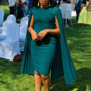 Close-up of elegant pleated cape sleeves on a dark teal formal evening party dress