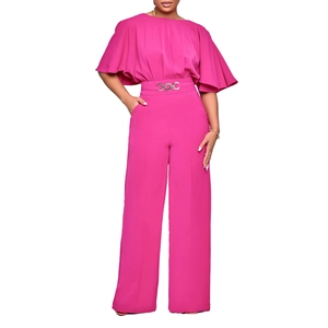 Detail of rose pink wide-leg jumpsuit featuring cape sleeves and a metal chain belt