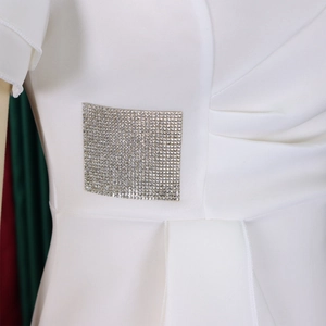 Detail of white dress featuring elegant side ruffles and a luxury crystal buckle