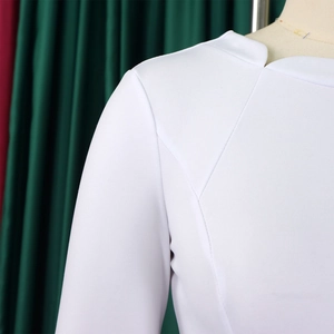 Détail de la robe blanche montrant l'encolure asymétrique et la texture du tissu tissé