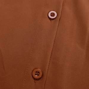Close-up of classic four-hole buttons and fine stitching on caramel shirt placket