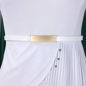 Détail de la taille avec boucle en métal doré et boutons en strass sur une robe blanche