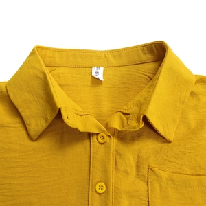 Detailed close-up of mustard yellow cotton linen shirt with collar and button pocket