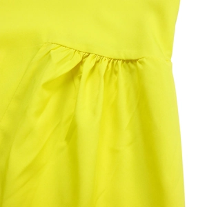 Detailed view of neon yellow woven fabric with fine pleats and pleated seam stitching