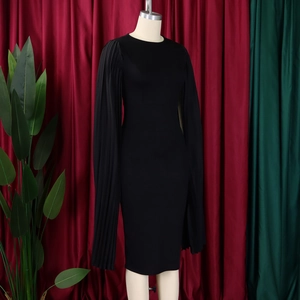Detail of elegant black sheath dress featuring pleated cape sleeves and a classic crew neck
