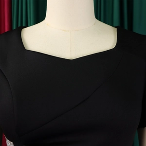 Detail of elegant black dress with asymmetrical neckline and ruffled solid fabric