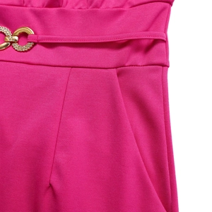 Detail of fuchsia wide-leg jumpsuit showing gold rhinestone buckle and pleated waist