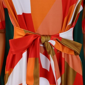 Détail de la ceinture nouée sur robe imprimée géométrique aux motifs rouges et oranges