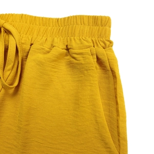 Detail of bright yellow casual shorts showing elastic drawstring waist and fabric texture