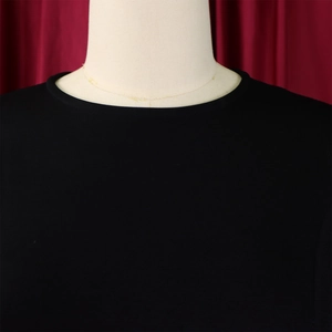 Close-up of elegant pleated neckline on black round neck party dress on mannequin
