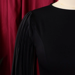 Detail of pleated puff sleeves and round neckline on a black evening party dress