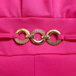 Detailed close-up of rose red knit fabric waist with sparkling rhinestone gold buckles