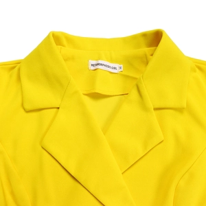 Detail of a bright yellow blazer dress with a lapel collar and brand label on the neck