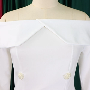 Detail of off-shoulder white dress with elegant overlapping collar and pearl bead clusters