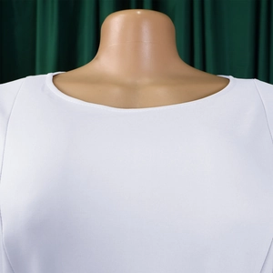 Détail de la robe blanche à col rond et manches bouffantes sur mannequin, texture premium