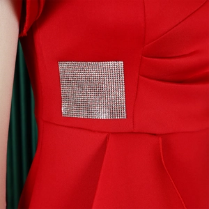 Detail of red fitted dress featuring a square rhinestone buckle and waist pleats