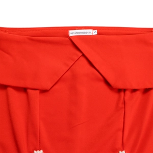 Detail view of red fabric with METAMORPHOSIS GIRL brand label and pearl accents
