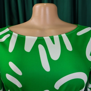 Detail of green African print dress featuring abstract white patterns and round neckline
