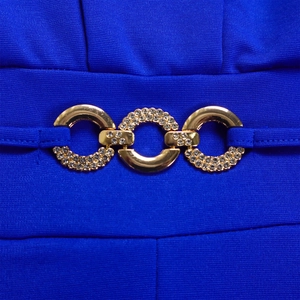 Close-up of royal blue jumpsuit waist with interlocking gold rhinestone rings