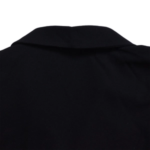 Detail of classic black blazer lapel featuring structured fabric and fine texture