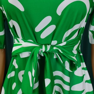 Detailed view of green African print dress featuring a tied waist bow and abstract patterns